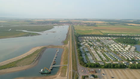 High-Establishing-Drone-Shot-Down-the-Line-Looking-Back-to-Wells-Next-The-Sea-with-Creek-at-High-Tide-and-Static-Caravan-Holiday-Home-Park