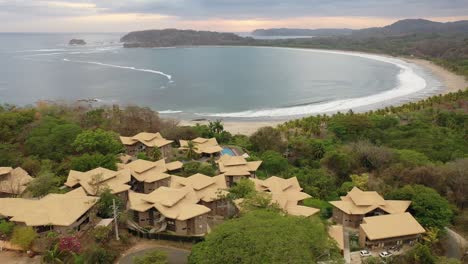 Hotel-Nammbu-in-Playa-Carrillo-Beach-with-half-moon-curved-shore,-Aerial-dolly-out-shot