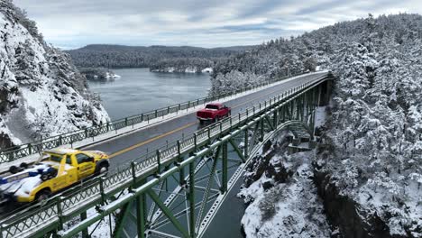 Drone-shot-of-trucks-driving-across-a-bridge-in-the-winter