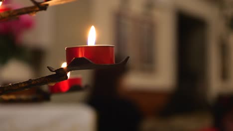 Brennende-Kerzen-In-Roten-Kerzenhaltern-In-Der-Kirche,-Wehende-Flammen