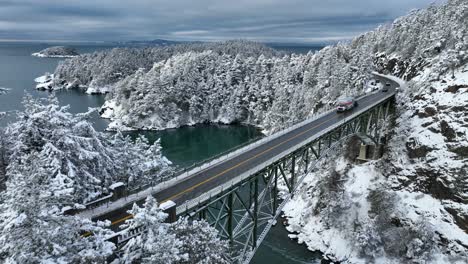 Aerial-view-of-a-U-Haul-moving-truck-passing-over-Deception-Pass-bridge-with-snow-covering-the-ground
