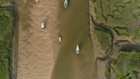 Top-Down-Drone-Shot-Flying-Over-Tidal-Creek-at-Low-Tide-with-Salt-Marsh-and-Sailing-Boats-in-Wells-Next-The-Sea-North-Norfolk-UK-East-Coast