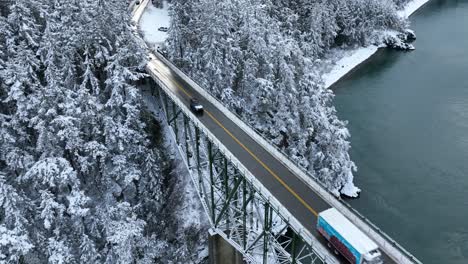Aerial-view-of-a-semi-truck-transporting-goods-in-the-winter-over-a-tall-steel-bridge