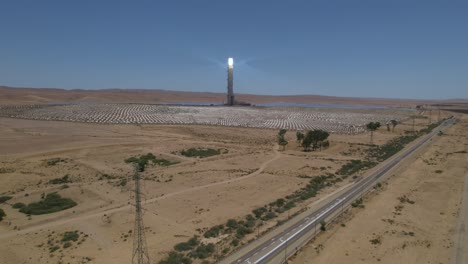 Aerial-rising-up-shot-in-front-of-Concentrated-solar-power-in-a-desolate-desert-near-a-road