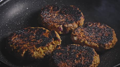Spraying-oil-on-brown-fried-tuna-fritters-in-black-pan-and-closing-the-frying-pan-with-lid