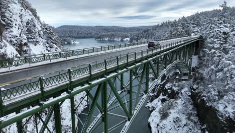Aufsteigende-Aufnahme-Der-Schneebedeckten-Deception-Pass-Brücke,-über-Die-Autos-Fahren