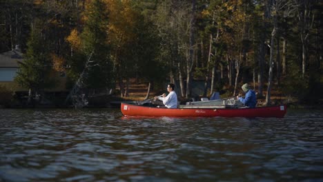 Zwei-Junge-Männer,-Die-In-Der-Herbstsaison-Auf-Einem-See-Ein-Kanu-Paddeln