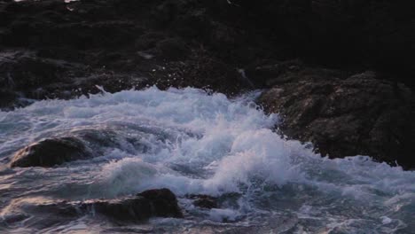 Waves-crashing-on-a-rocky-coastline-at-sunset-in-slow-motion