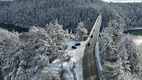 Drone-shot-of-cars-driving-across-Deception-Pass-bridge-in-the-snow