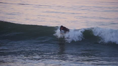 Junger-Mann-Surft-Bei-Sonnenaufgang-Und-Macht-Tricks-Mit-Einem-Surfbrett