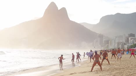 Der-Berühmte-Copacabana-strand-Und-Die-Berühmten-Berge-Im-Hintergrund-Mit-Menschen,-Die-Frescobol-Spielen