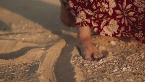 Close-up-shot-of-a-woman-in-a-dress-pushing-one-foot-backwards-in-the-sand