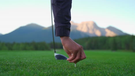 Golfer-placing-tee-on-green-golf-course-in-the-rocky-mountains-of-Banff-and-Kananaskis-of-Alberta,-Canada