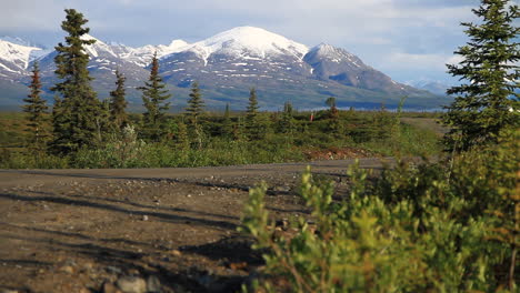 Schneebedeckte-Berge-Im-Hintergrund-Der-Unbefestigten-Straße-In-Der-Wildnis-Von-Alaska