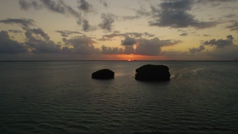 Drone-shot-of-small-islands-off-the-coast-of-Cancun,-Mexico-during-a-beautiful-warm-sunset