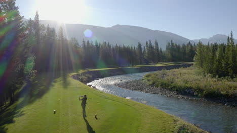 Drone-shot-of-drive-on-green-golf-course-in-the-rocky-mountains-of-Banff-and-Kananaskis-of-Alberta,-Canada