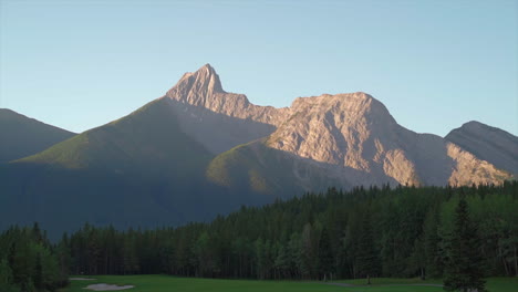 Mountain-peaks-on-green-golf-course-in-the-rocky-mountains-of-Banff-and-Kananaskis-of-Alberta,-Canada