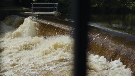 Flusswasser-In-Zeitlupe,-Das-über-Einen-Damm-Fließt,-Rauschendes-Wasser,-Das-Wellen-über-Einer-Fischtreppe-Erzeugt
