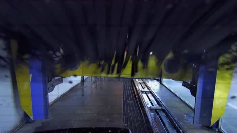 Automatic-car-wash-as-seen-from-rear-of-vehicle-moving-through-machine-rollers