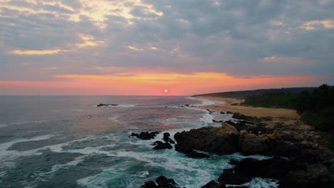 Antenne-über-Felsiger-Küste-Und-Blick-Auf-Den-Strand-Von-Playa-Paraiso-Mit-Majestätischem-Orangefarbenem-Sonnenuntergang-Am-Horizont