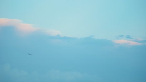Avión-Volador-En-Un-Hermoso-Cielo-Azul,-Nubes-De-Surf-Al-Atardecer,-Video-4k