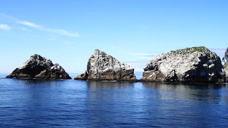 Drei-Felseninseln-Spiegeln-Sich-In-Einem-Ruhigen,-Wunderschönen-Blauen-Ozean-Wider