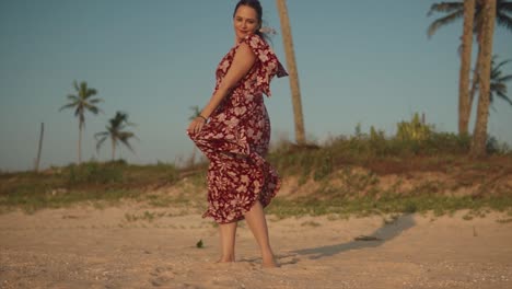 Frau-In-Einem-Kleid-Wirbelt-Und-Lächelt-An-Einem-Strand-Mit-Bäumen-Im-Hintergrund