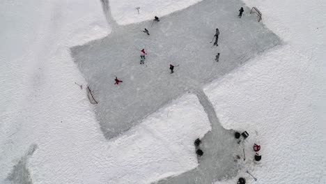 Overhead-aerial-drone-view-of-kids-playing-hockey-on-a-frozen-pond