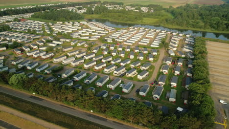 Establishing-Rising-Drone-Shot-of-Static-Caravan-Holiday-Home-Park-with-Small-Lake-and-Trees-in-North-Norfolk-UK-East-Coast