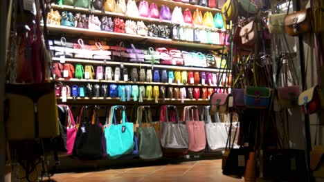 Store-in-Rome,-Italy-selling-purses-and-handbags-with-video-establishing-shot-at-night