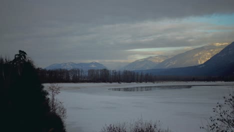 Golden-Hour-Hyperlapse-of-Dense-Clouds-Over-Snow-Covered-Mountains-and-Frozen-North-Thompson-River-Near-Little-Fort,-BC