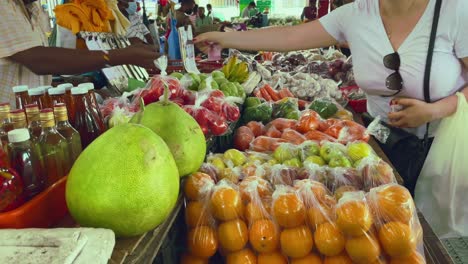 Client-paying-fruits-in-the-Sir-Selwyn-Clarks-in-market-in-Victoria-town-on-Mahe,-Seychelles,-paying-the-oranges-with-the-local-currency