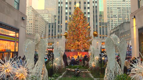 Crowd-Of-People-Around-The-Rockefeller-Center-Christmas-Tree-Decorated-With-Angels-In-Foreground