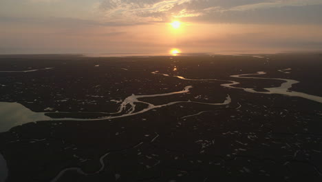 Establishing-Cinematic-Drone-Shot-of-Natural-Salt-Marsh-and-Creek-at-High-Tide-with-Winding-Waterways-at-Stunning-Orange-Sunrise-in-North-Norfolk-UK-East-Coast
