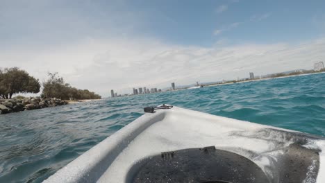 FPV-of-a-kayak-drifting-in-the-ocean-near-jet-skis-towards-a-city-skyline