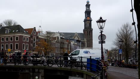 Slow-motion-shot-of-cars-and-pedestrian-crossing-bridge-above-canals-in-Amsterdam-during-cloudy-day