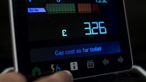 Close-Up-Of-Finger-Pressing-Touchscreen-Display-Of-UK-Energy-Smart-Meter-To-Check-Costs-Of-Electricity-And-Gas-Usage