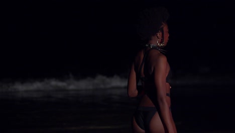 Sexy-bikini-babe-on-the-beach-at-night-spins-in-her-outfit-with-waves-in-the-background