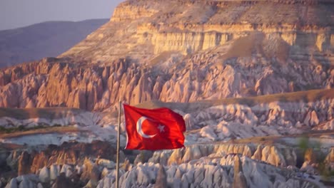 Bandera-Turca-Ondeando-En-Capadocia-Con-El-Valle-Rojo-Al-Fondo