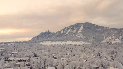 Hoher-Drohnenschuss,-Der-Sich-Rechts-Von-Boulder-Colorado-Und-Felsigen-Flatiron-Mountains-Bewegt,-Nachdem-Ein-Großer-Winterschneesturm-Bäume,-Häuser,-Straßen-Und-Nachbarschaften-In-Frischem-Weißen-Schnee-Bedeckt