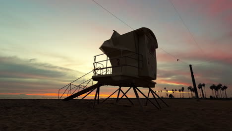A-colorful-sunrise-with-a-lifeguard-tower-in-silhouette-in-the-foreground-at-Cabrillo-Beach,-San-Pedro-California---time-lapse