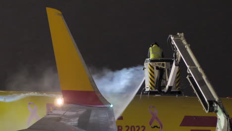 Brno-airport-support-staff-employee-deicing-DHL-plane-at-night