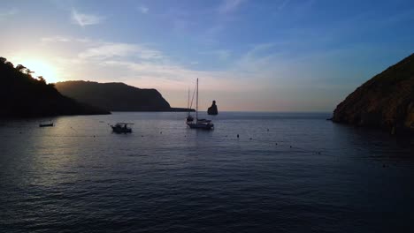 Sonnenuntergang-Hinter-Klippen-Segelboot-Silhouette