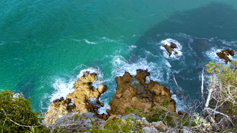 Waves-crash-against-jagged-coastline---top-view-from-lookout-point,-The-Heads