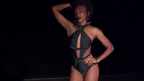 Eine-Schwarze-Junge-Frau-In-Einem-Sexy-Bikini-Genießt-Eine-Nacht-Am-Strand-Mit-Meereswellen-Im-Hintergrund