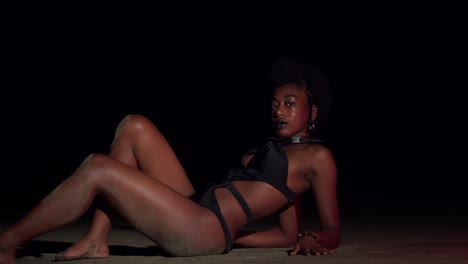 Young-black-girl-lays-in-the-sand-on-a-Caribbean-beach-at-night