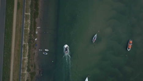 Top-Down-Drone-Shot-of-Small-Working-Fishing-Boat-Travelling-Through-Creek-Harbour-with-Other-Small-Sailing-Boats-on-UK-East-Coast
