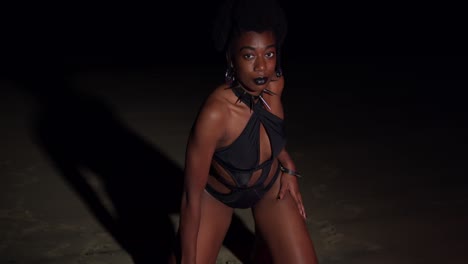 Bikini-gothic-girl-kneels-in-the-sand-on-the-beach-at-night