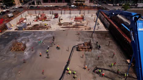 People-working-on-the-first-floor-at-a-project-site---reverse,-tilt,-aerial-view