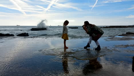 Mother-takes-photo-of-her-little-daughter-by-the-rough-sea